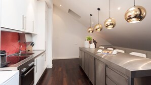 A modern kitchen with stainless steel appliances, a red backsplash, and pendant lighting.