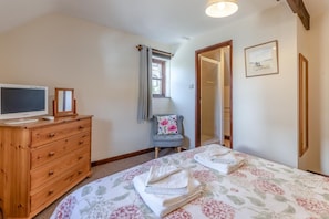 A bedroom with a bed, a dresser, a television, a chair, and a door leading to another room. - 4 Bed in Westward Ho! (oc-n1623) (Westward Ho!)