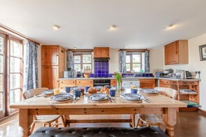 A kitchen with wooden cabinets, a dining table set for four, and a view of the outside.