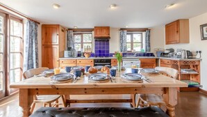 Una cucina con mobili in legno, un tavolo da pranzo per quattro persone e vista sull'esterno.