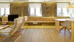 A cozy room with a stone wall, wooden furniture, a television, and a window. - Santa María by FeelFree Rentals (San Sebastián)