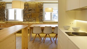 A modern kitchen with a stone wall, wooden table, and chairs. - Santa María by FeelFree Rentals (San Sebastián)