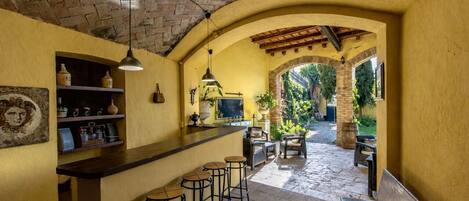 Una cocina rústica con barra, suelo de piedra y vistas a un jardín.