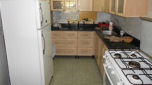 Une cuisine de taille réduite, dotée de meubles en bois, d’un réfrigérateur blanc, d’une cuisinière et d’un évier.