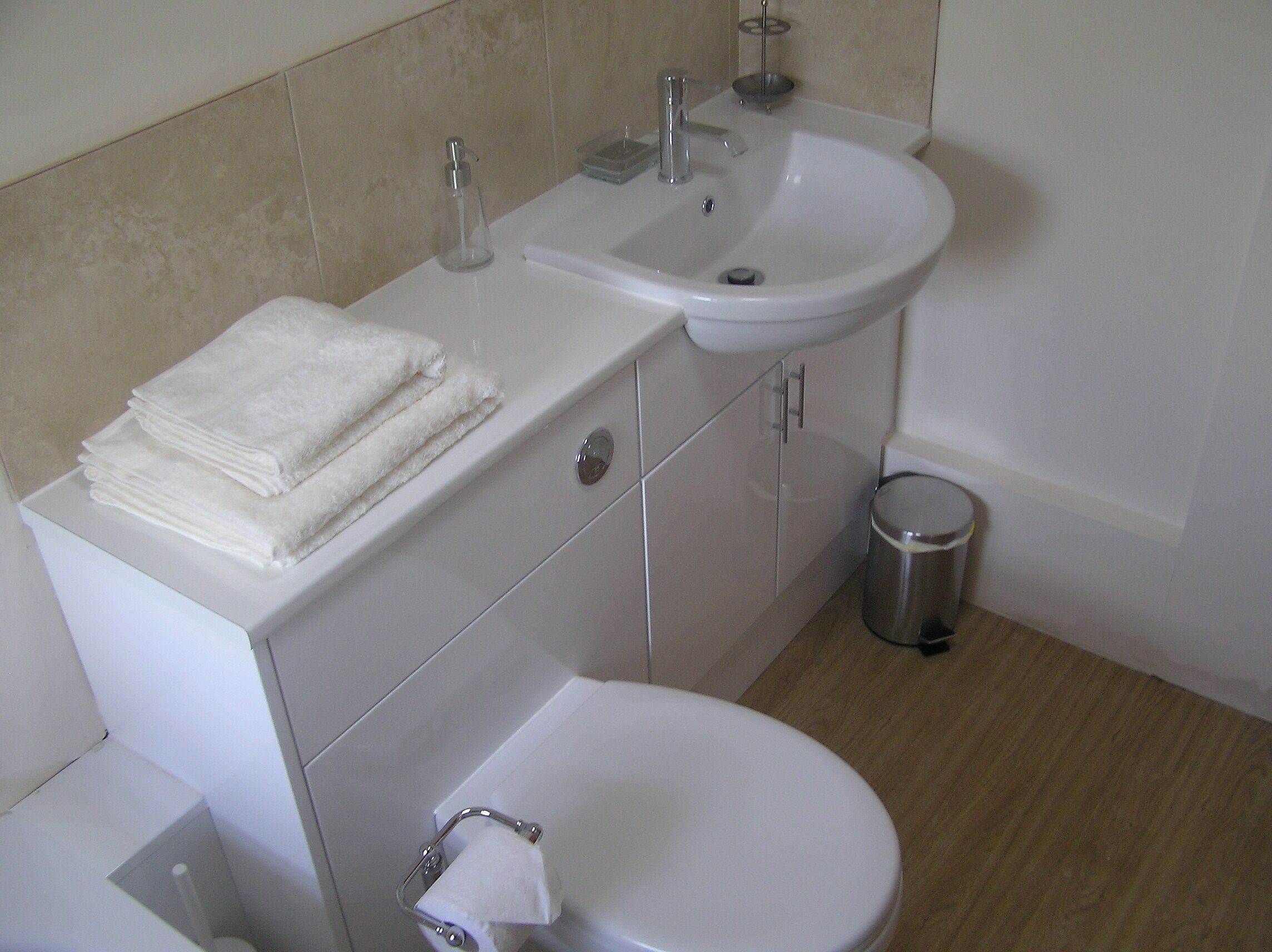 A bathroom with a sink, toilet, and a trash bin.