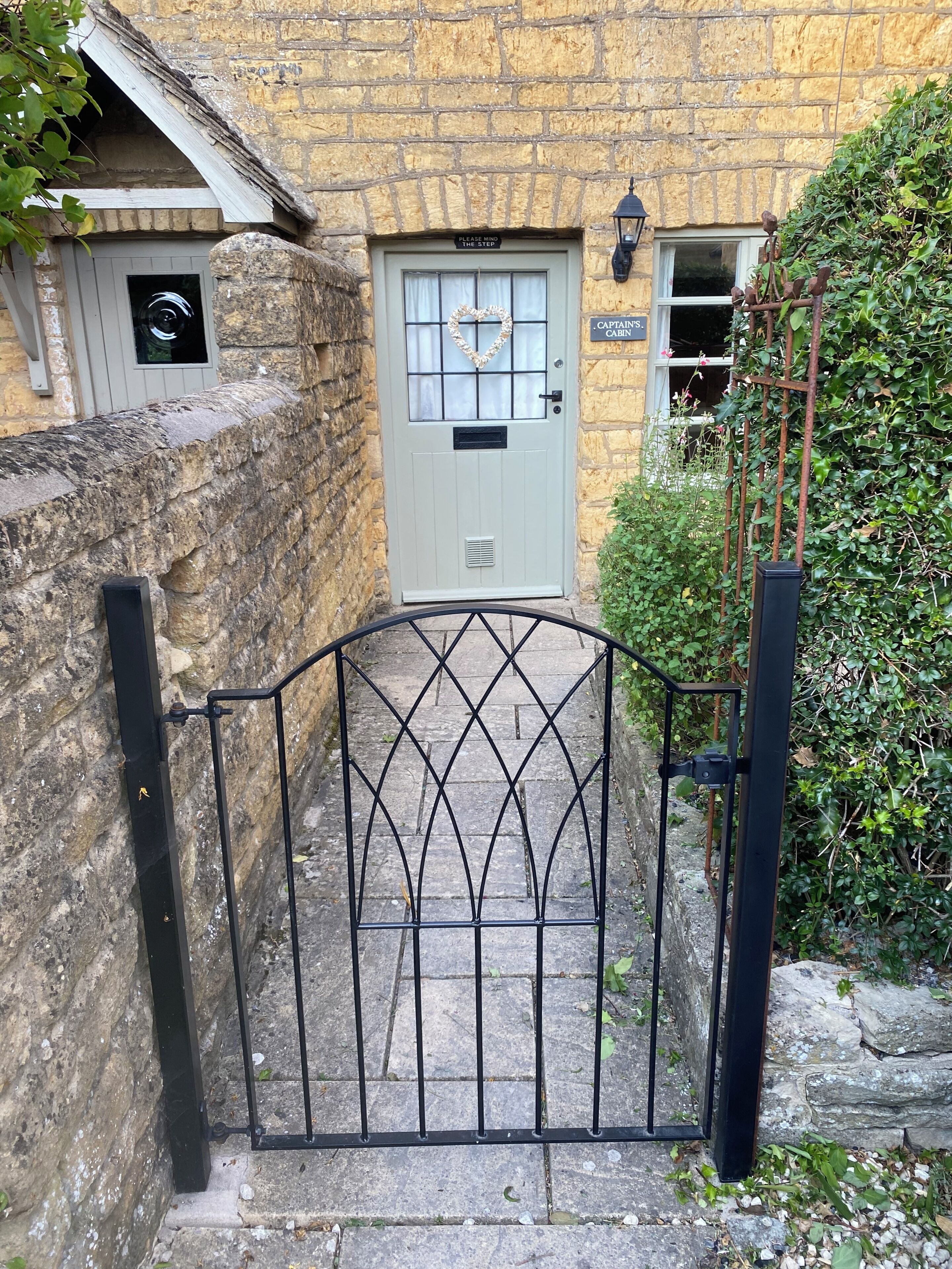 A stone wall, a metal gate, a door with a sign, and a small window.