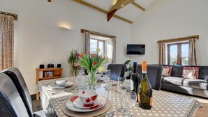 Un coin repas avec une table dressée pour quatre personnes, un canapé, un téléviseur et une bibliothèque.
