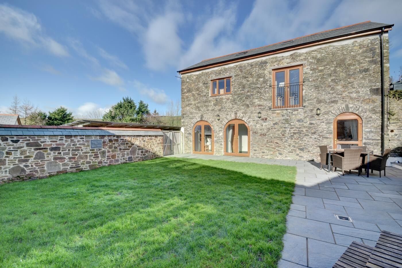 A stone building with a grassy yard and outdoor seating.