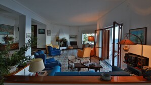 Een ruime woonkamer met blauwe banken, een schaakspel en een televisie.