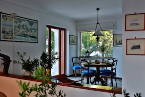 A dining area with a wooden table, blue cushioned chairs, and a hanging light fixture.