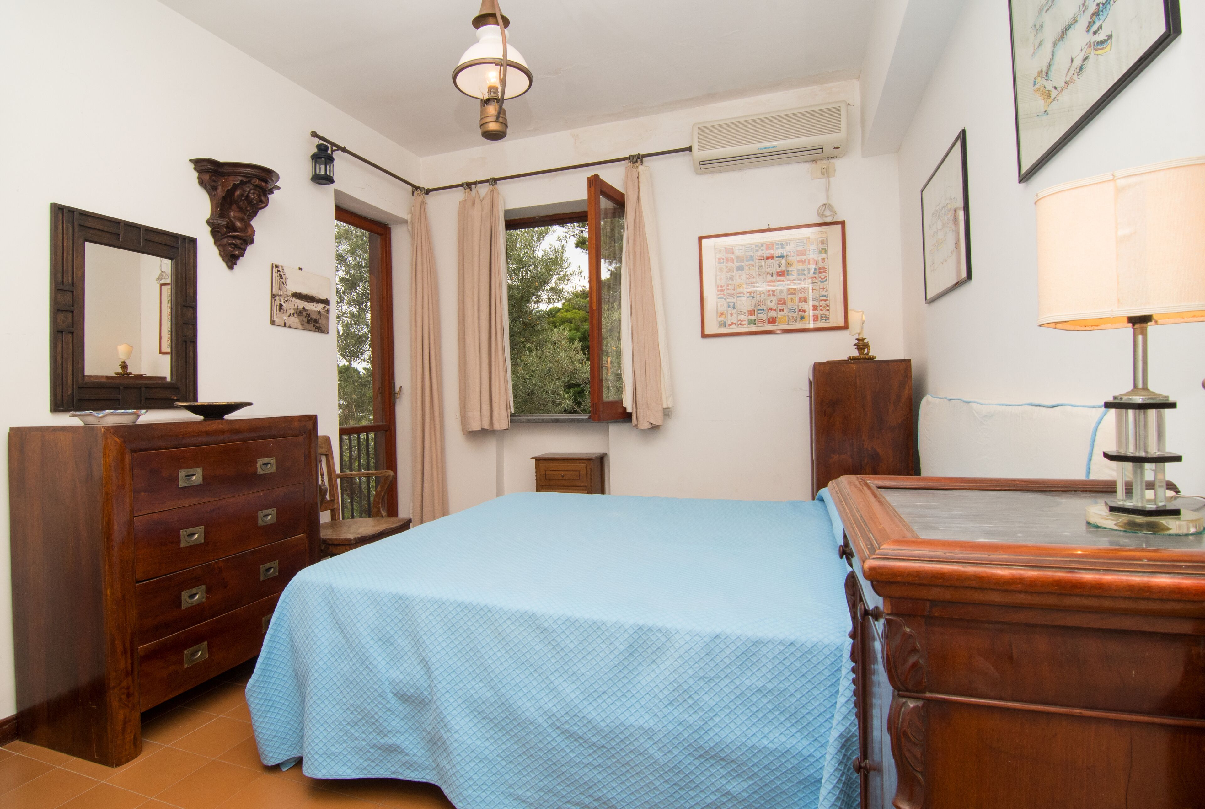 Een slaapkamer met een bed, een ladekast en een spiegel.