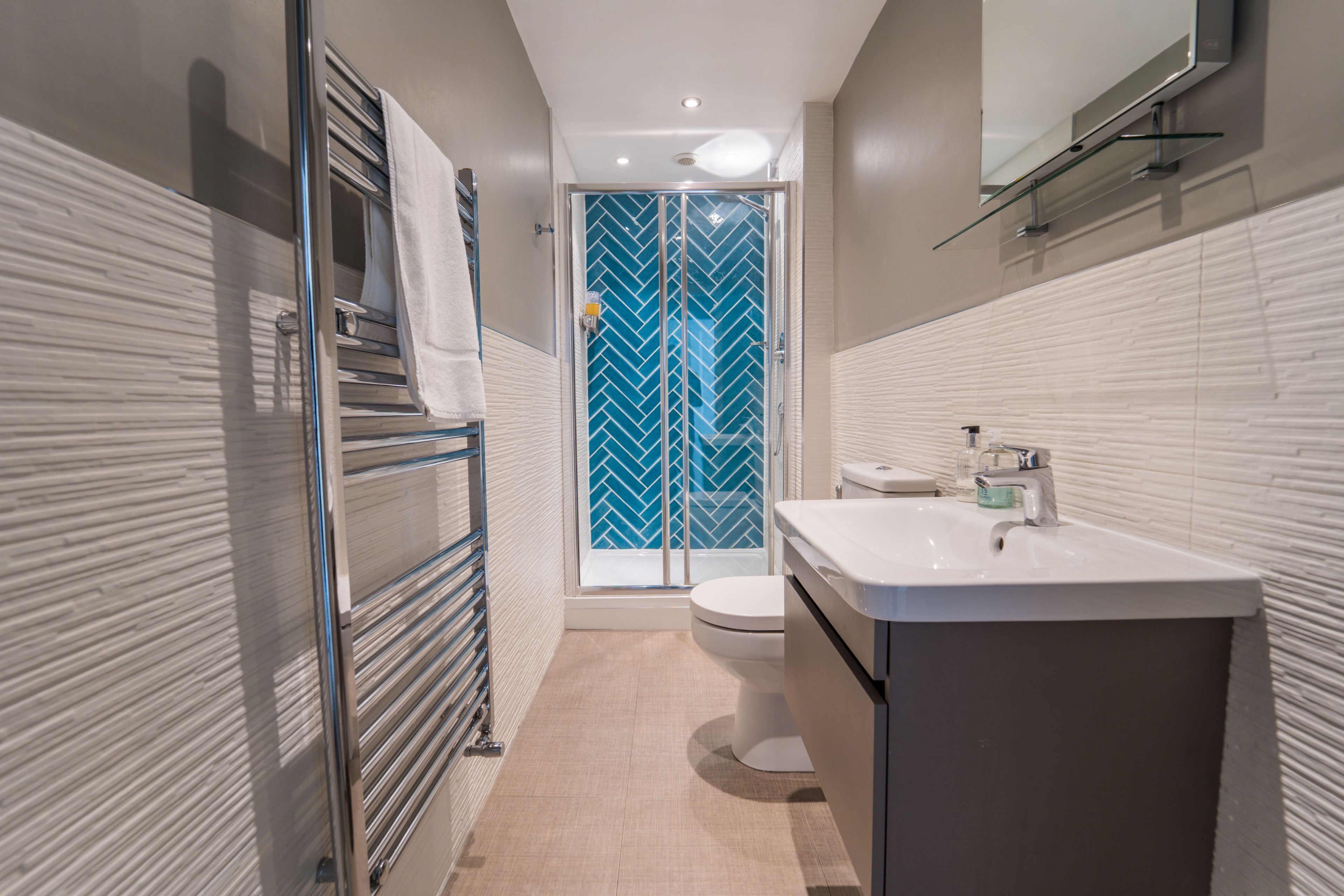 A modern bathroom with a glass shower door, a white sink, and a toilet.
