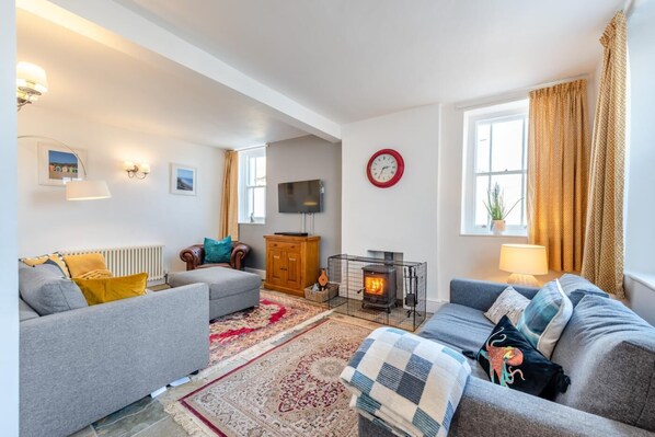 A cozy living room with a fireplace, sofas, and a television.