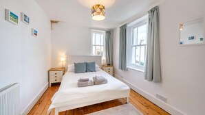 Une chambre à coucher avec un lit, des tables de chevet, une lampe et une fenêtre avec des rideaux.