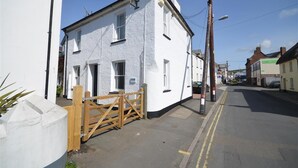 A white building with a gated entrance, a clear sky, and a street in the background.