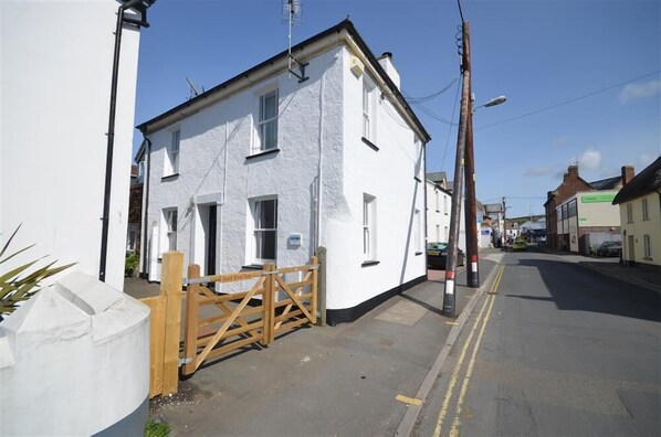 A white building with a gated entrance, a clear sky, and a street in the background. - 3 Bed in Braunton (oc-soufar) (Braunton)
