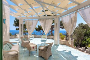 Un porche cubierto con muebles de mimbre y vistas al mar.
