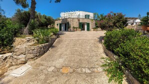 A circular stone building with a central courtyard, surrounded by greenery and a clear sky.