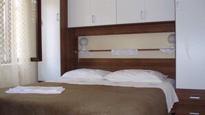A bedroom with a bed, a wooden headboard, a wardrobe, and a window with curtains. - Stone House Gregov, Lumbarda 317- Hr (Unknown)