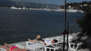 A poolside area with lounge chairs and a water view. - Stone House Gregov, Lumbarda 317- Hr (Unknown)