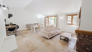Un salón espacioso con un sofá blanco, una mesa de comedor con sillas y una zona de cocina con mostrador y electrodomésticos.