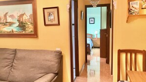 A living room with a sofa, a dining table, and chairs. There is a hallway leading to another room. - SANTO DOMINGO APARTMENT R030 (Benidorm)