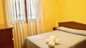 A single bed with a neatly folded towel, a wooden headboard, and a nightstand. - SANTO DOMINGO APARTMENT R030 (Benidorm)
