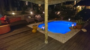 An outdoor swimming pool with a wooden deck, surrounded by potted plants and outdoor furniture. - A REAL HOME AWAY FROM HOME EXPERIENCE.... (Cape Town)