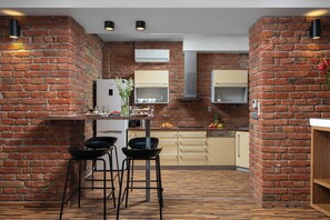 Una cocina con paredes de ladrillo, piso de madera y taburetes de bar modernos.