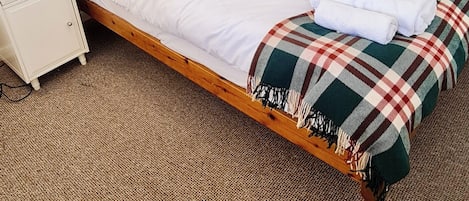 A neatly made bed with a plaid blanket, a bedside table with a lamp, and a wardrobe with mirrors.