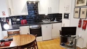 Un espacio habitable compacto con cocina, comedor y zona de estar con alfombra.