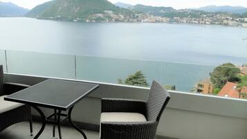 Ein Balkon mit Tisch und Stühlen, mit Blick auf einen See und Berge.
