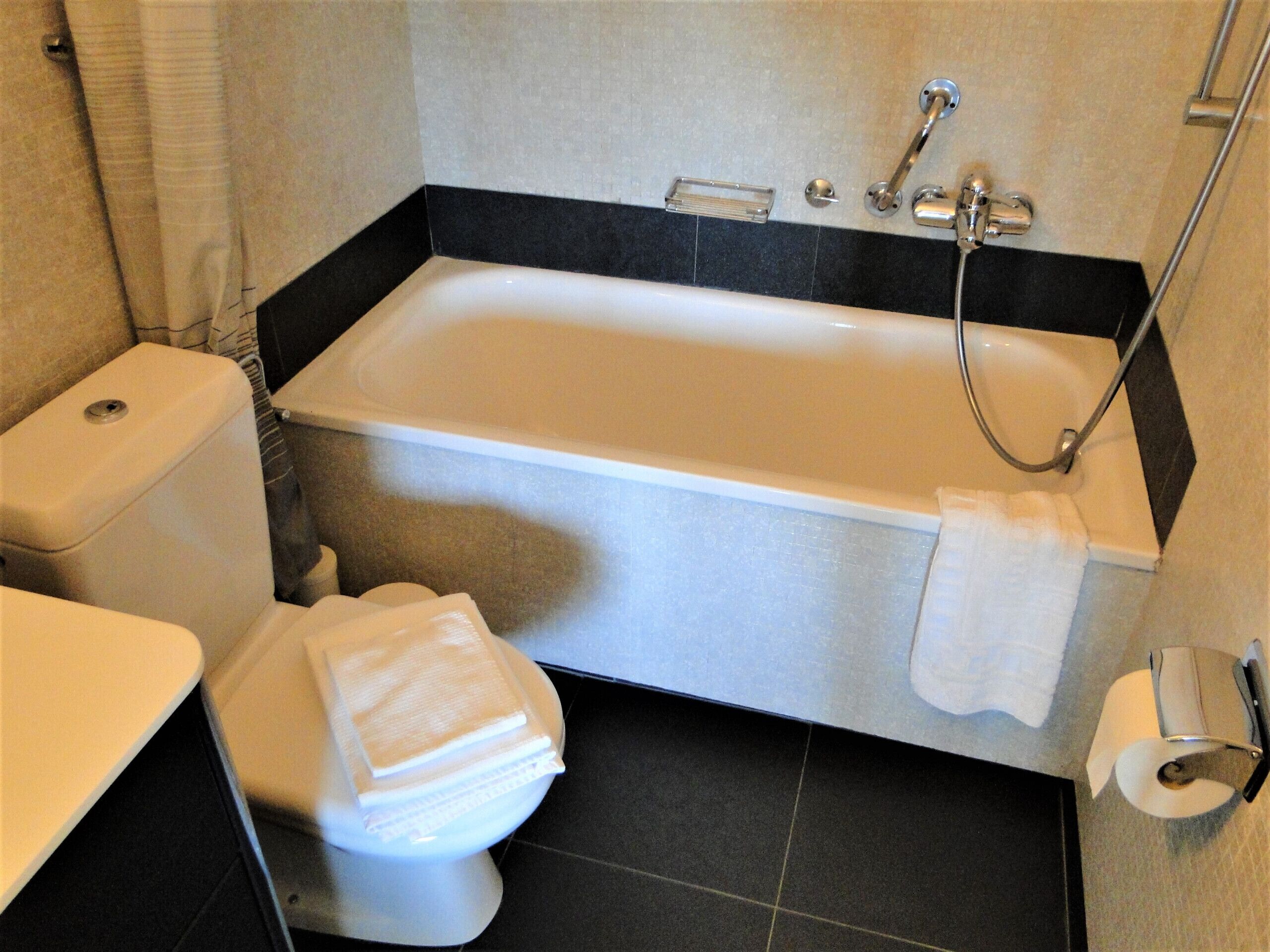 A bathroom with a bathtub, toilet, and a towel rack.