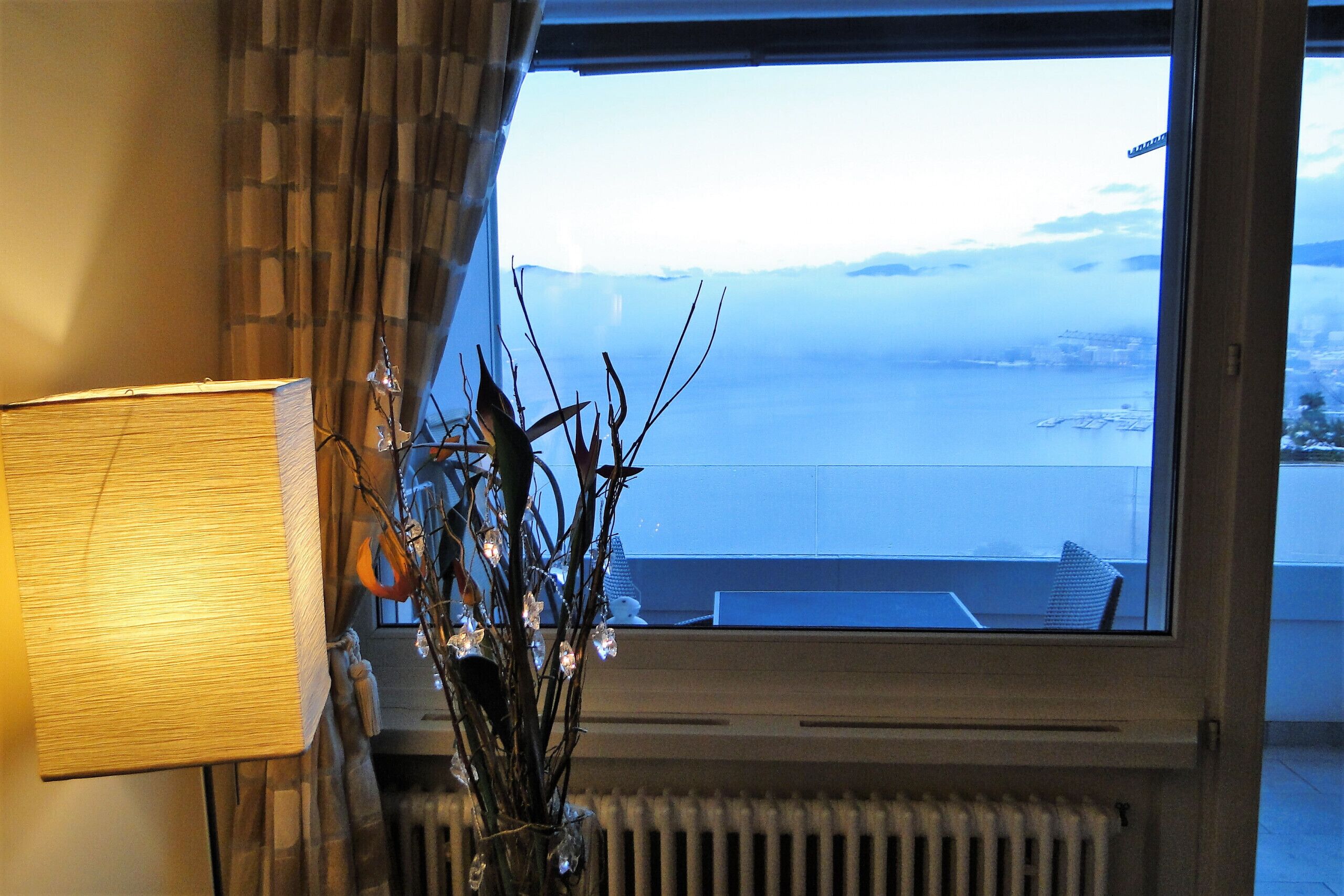 Een kamer met uitzicht op een wateroppervlak, een radiator en een lamp.