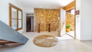 A spacious hallway with a stone wall, a wooden door, and a potted plant. - VILLA ES TRENC - SA SINIA VELLA (Campos)