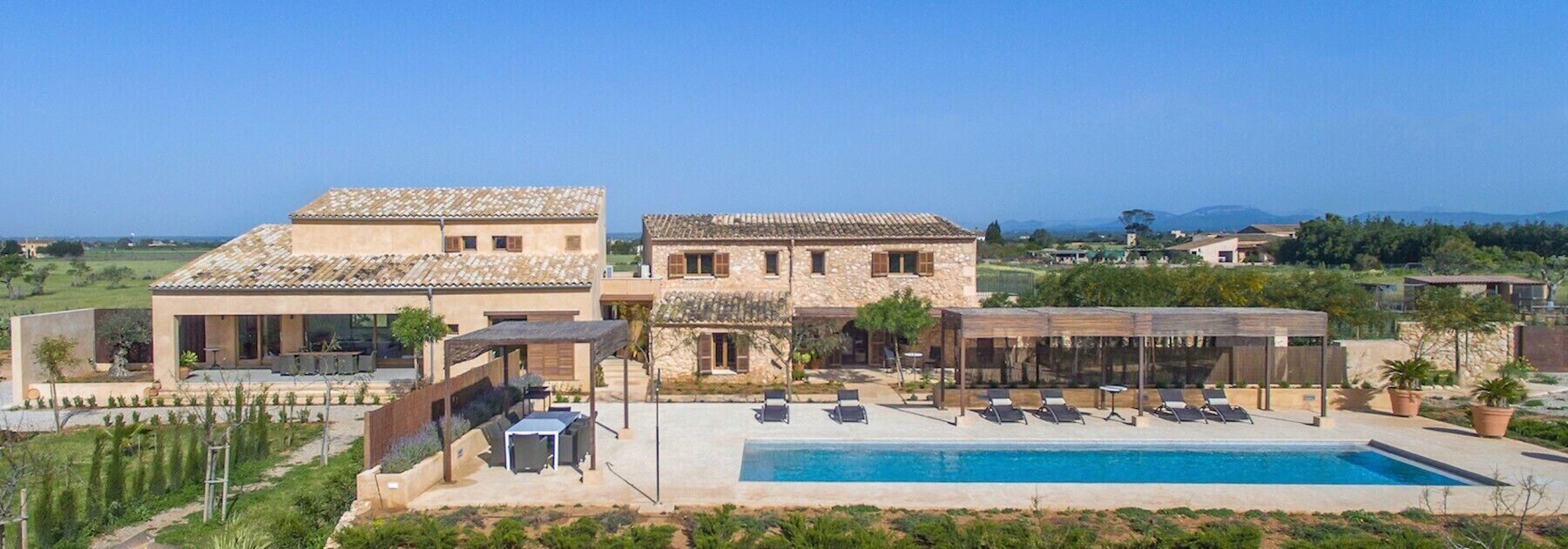 Une villa avec piscine, un espace extérieur aménagé et une vue sur la campagne.