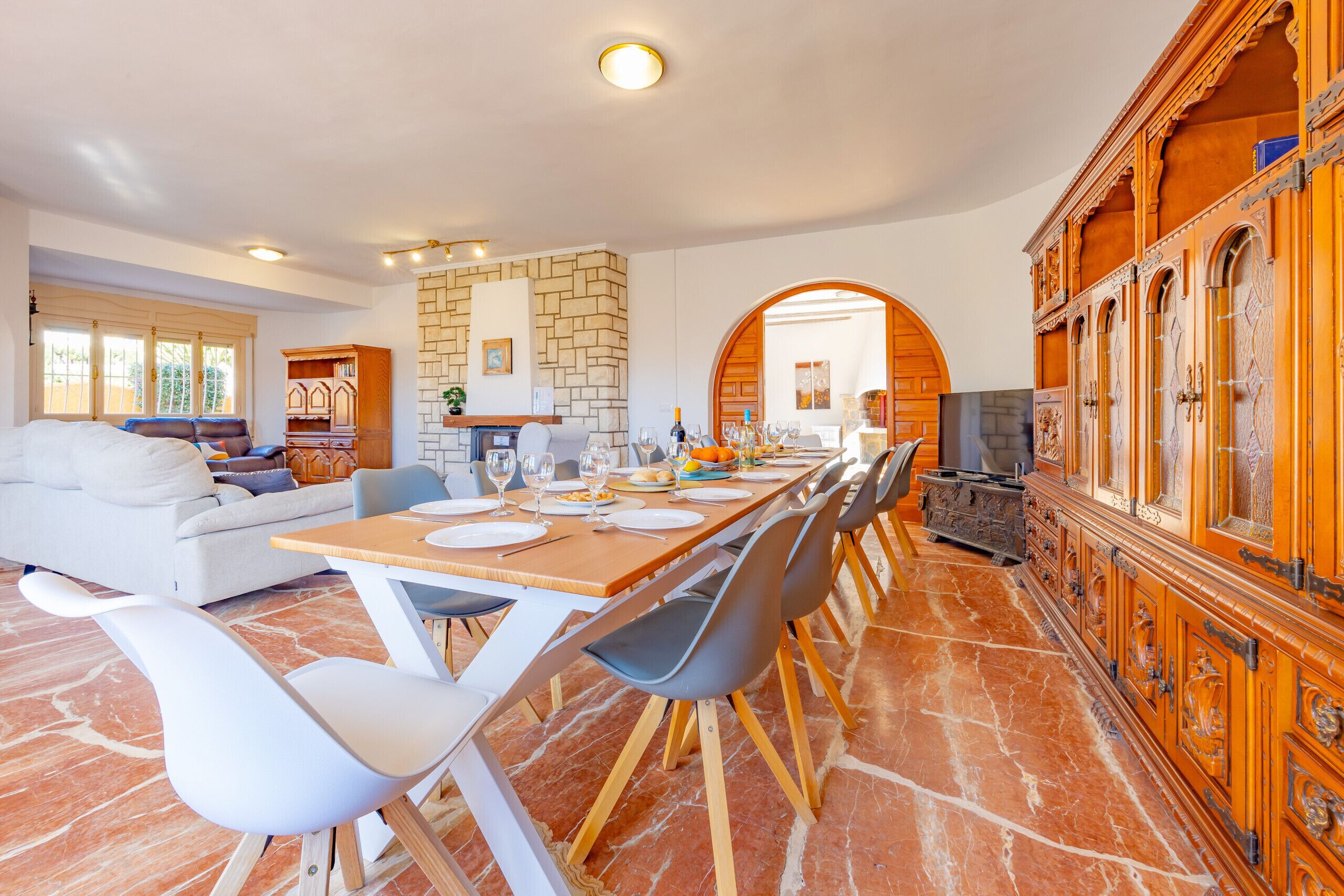 A spacious dining area with a long wooden table, modern chairs, and a stone fireplace.