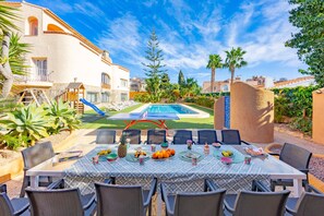 Ein Essbereich am Pool mit einem Tisch für sechs Personen, umgeben von Stühlen, mit einem Pool im Hintergrund.