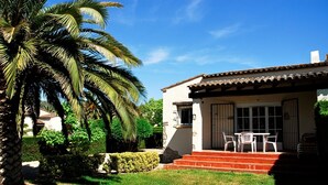 Une maison à deux étages avec un patio, une façade blanche et un toit rouge.