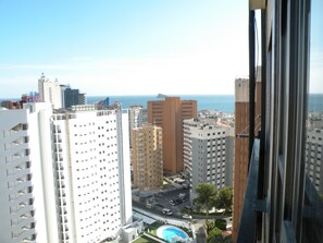 Un edificio de gran altura con varias plantas, una piscina y vista al mar.