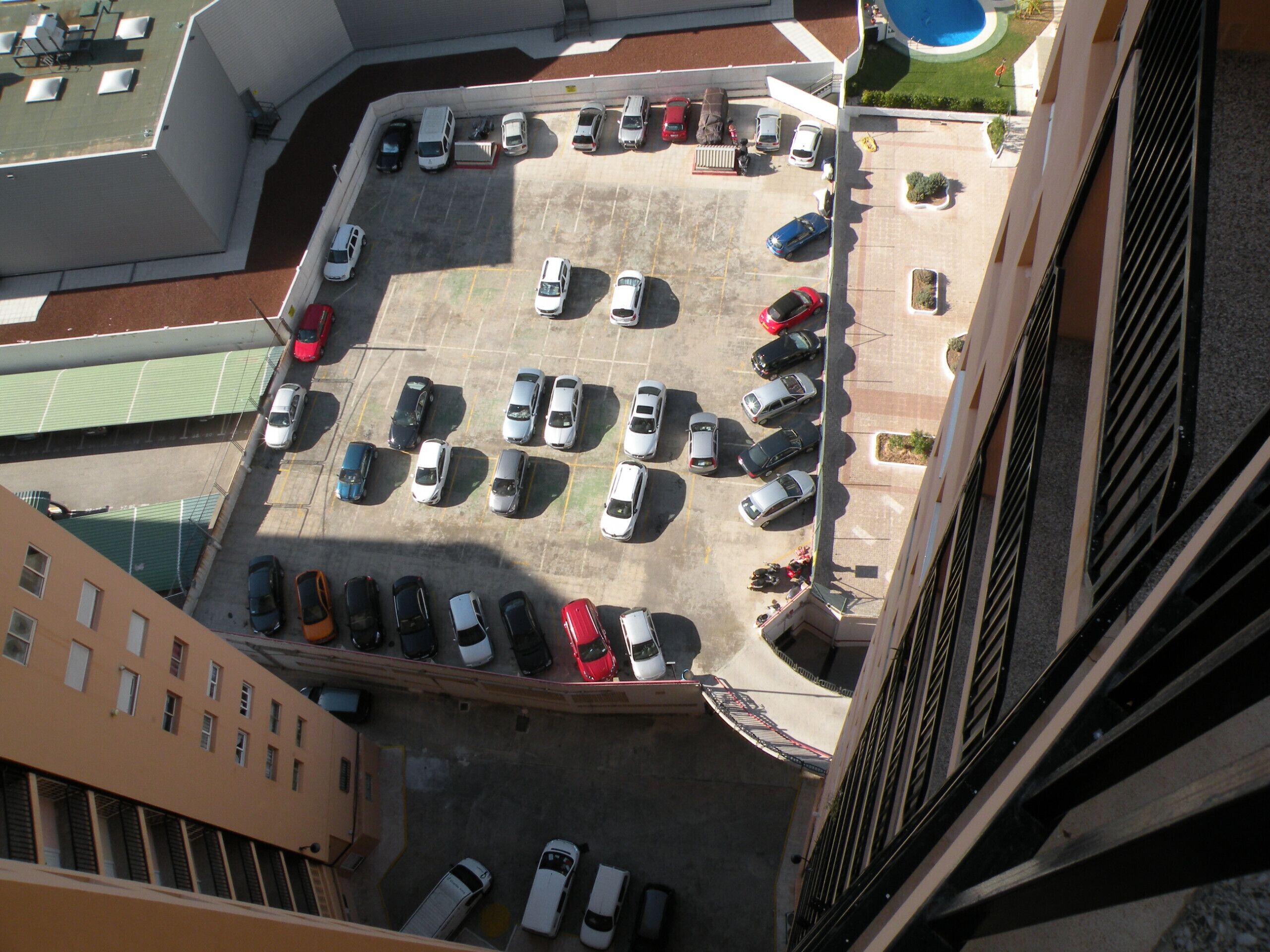 Vista aérea de un estacionamiento con varias filas de coches aparcados.