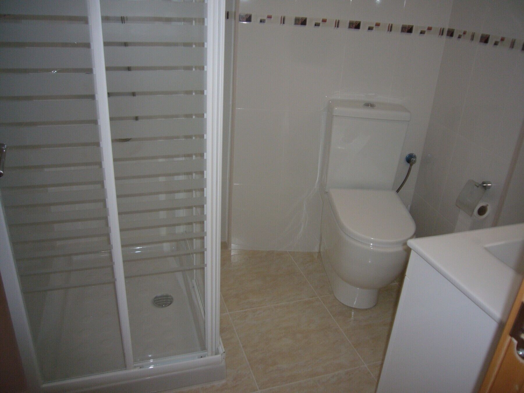 Une salle de bain avec une douche à parois de verre, des toilettes et un lavabo.