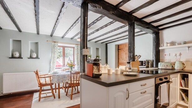 A kitchen with a central island, white cabinetry, and a rustic ceiling.