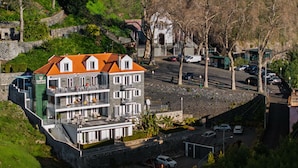 Ett hotell med flera våningar, balkonger, en parkeringsplats och en mur av sten.