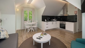 Ett kompakt bostadsutrymme med en matplats, ett litet kök och en liten sittgrupp.