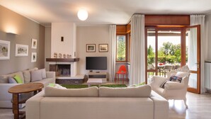 Un salon comprenant un canapé, un téléviseur, une cheminée et un coin repas avec une table et des chaises.