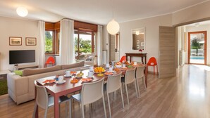 Un salon moderne comprenant un coin repas, un téléviseur à écran plat et une grande fenêtre agrémentée de rideaux.
