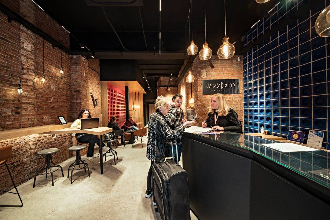 A cafe with brick walls, hanging pendant lights, and a counter with a menu.
