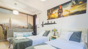 A hotel room with two beds, a cityscape mural, a city skyline view, and a decorative lamp. - Cubo's Villa Bellavista La Jona & Heated Pool / BBQ / wifi / fireplace / heated pool (Alhaurin de la Torre)