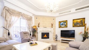 A living room with a fireplace, a television, and two sofas. - Cubo's Villa Bellavista La Jona & Heated Pool / BBQ / wifi / fireplace / heated pool (Alhaurin de la Torre)